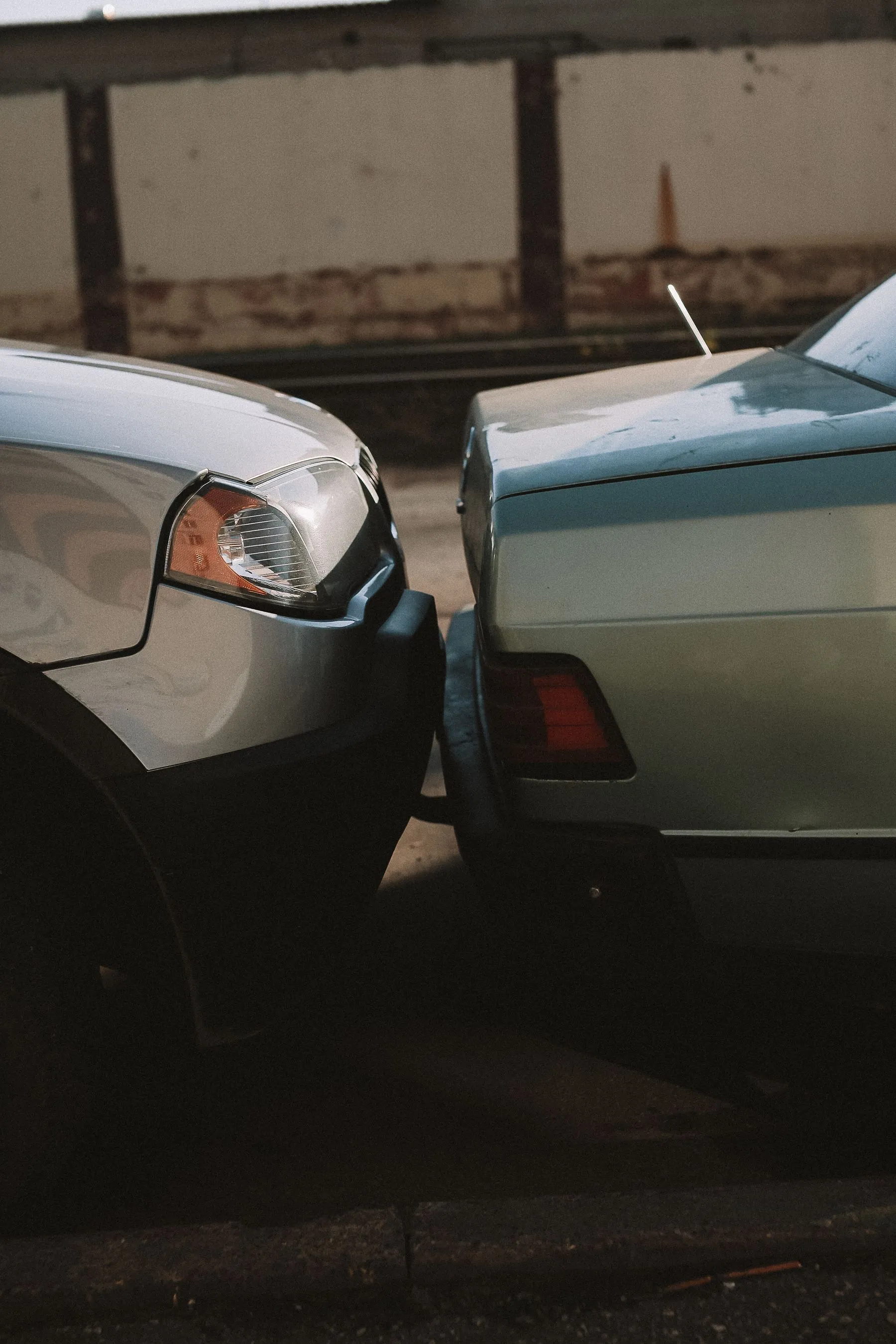 Close view of a silver car's front end pressed into the back of another car after a collision