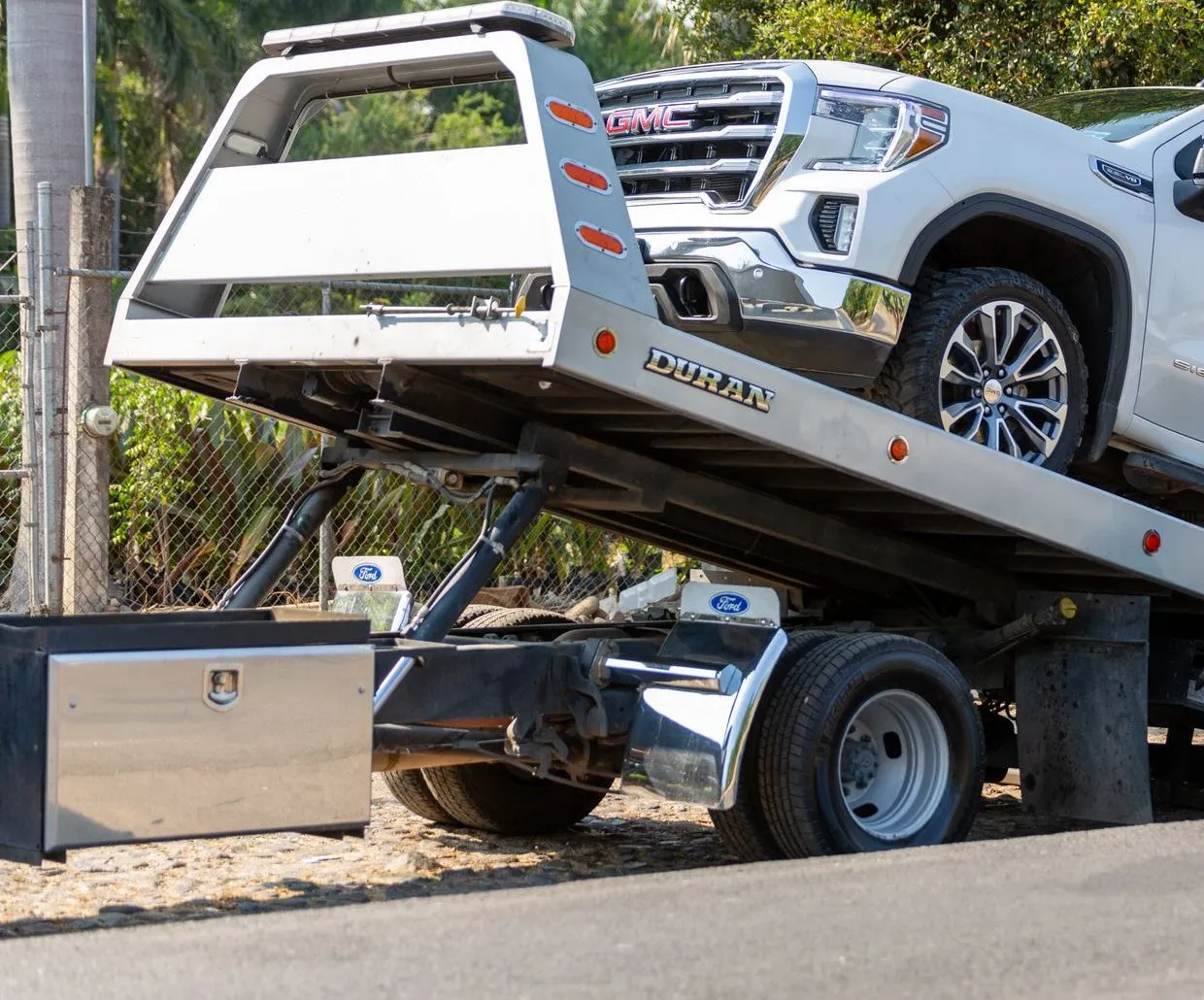 A white pickup being winched onto a flatbed tow truck