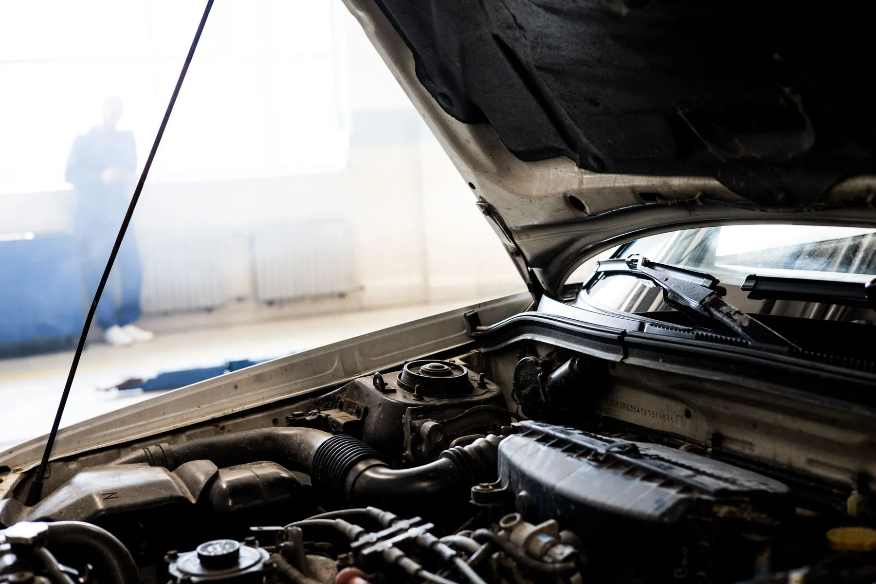 An older car with its hood propped open, showing the engine bay